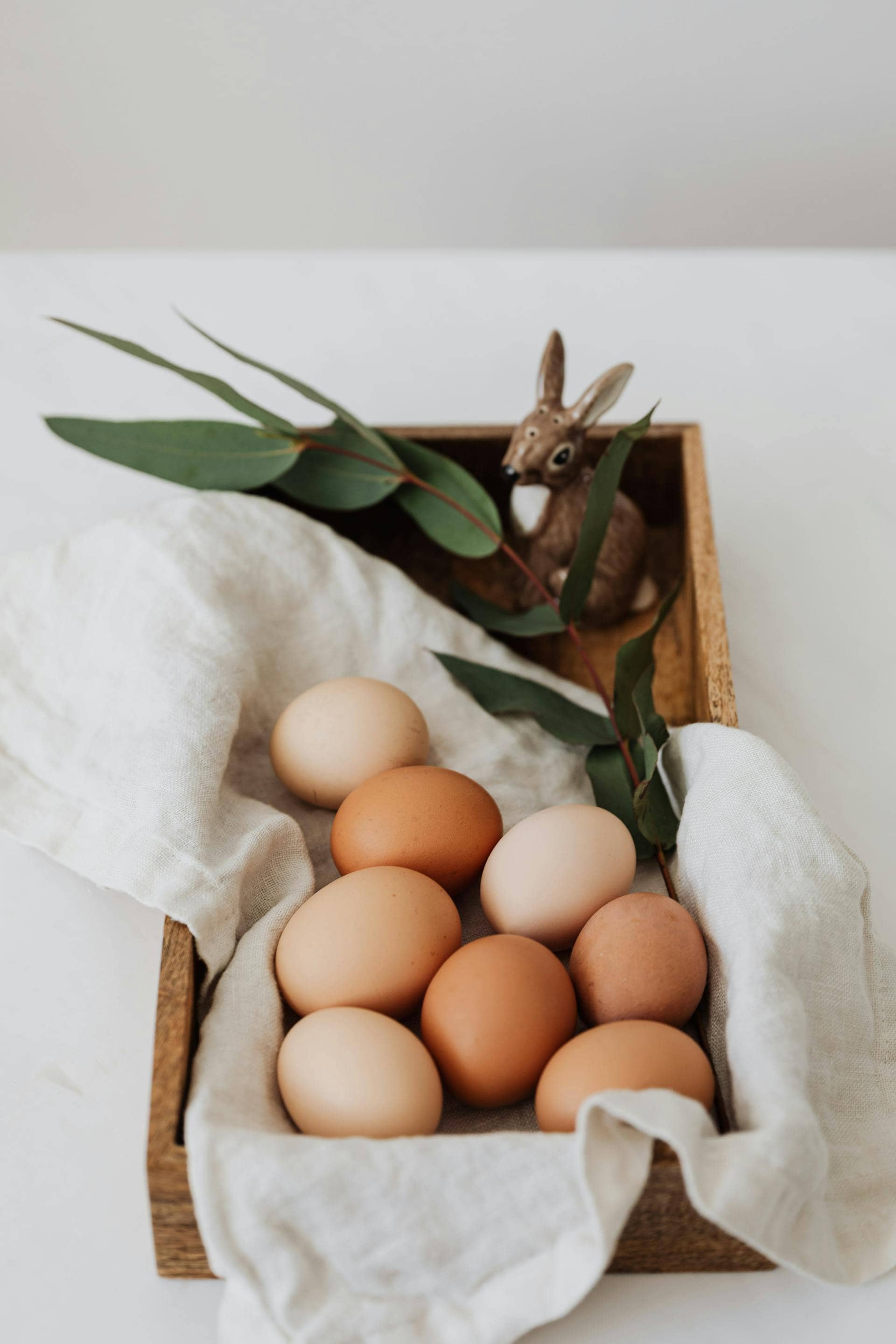 Brown and white eggs arranged in a wooden tray, representing a natural source of collagen-building nutrients like protein and amino acids.