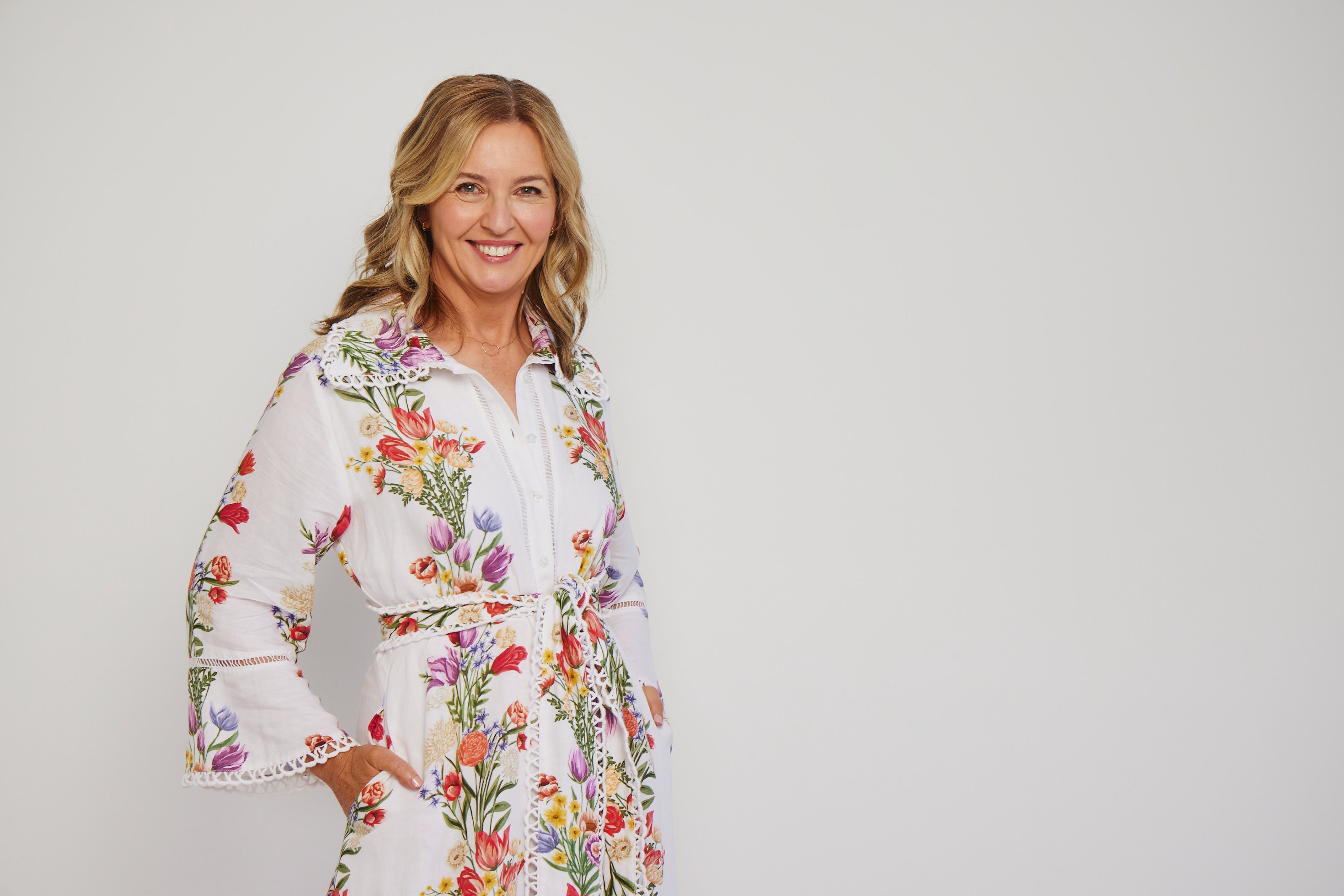woman in floral dress with blonde hair, smiling at camera