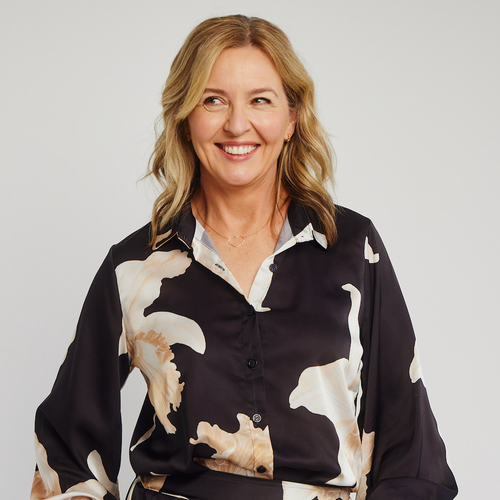woman with blonde hair in black shirt with large cream flowers