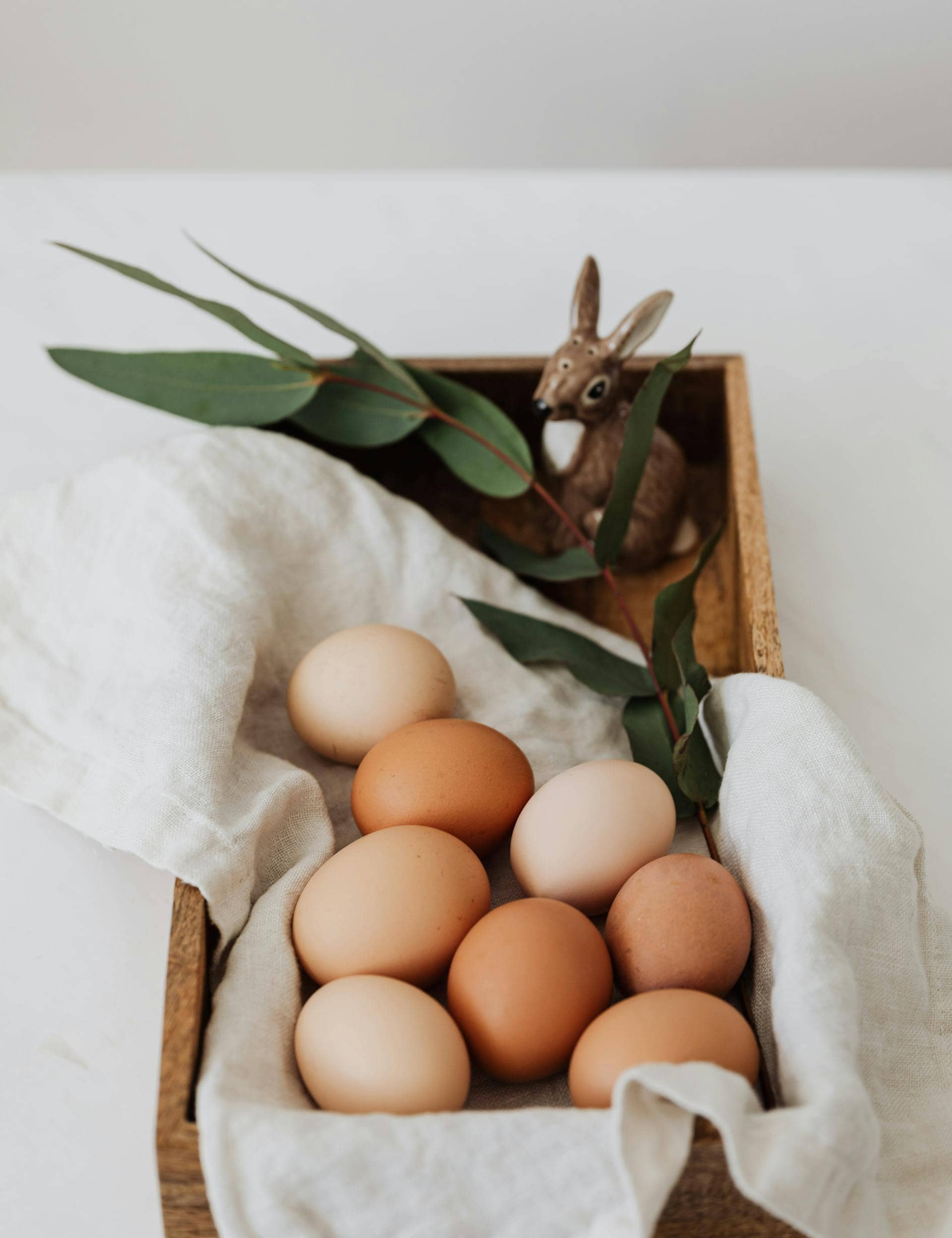 Brown and white eggs arranged in a wooden tray, representing a natural source of collagen-building nutrients like protein and amino acids.