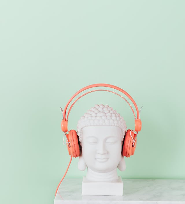 statue of a bust on a marble table wearing orange headphones. 