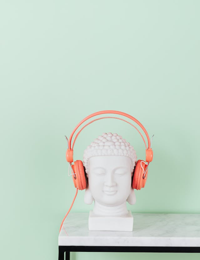 statue of a bust on a marble table wearing orange headphones. 