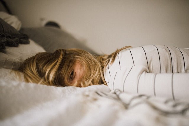 Woman lying face down on bed looking tired