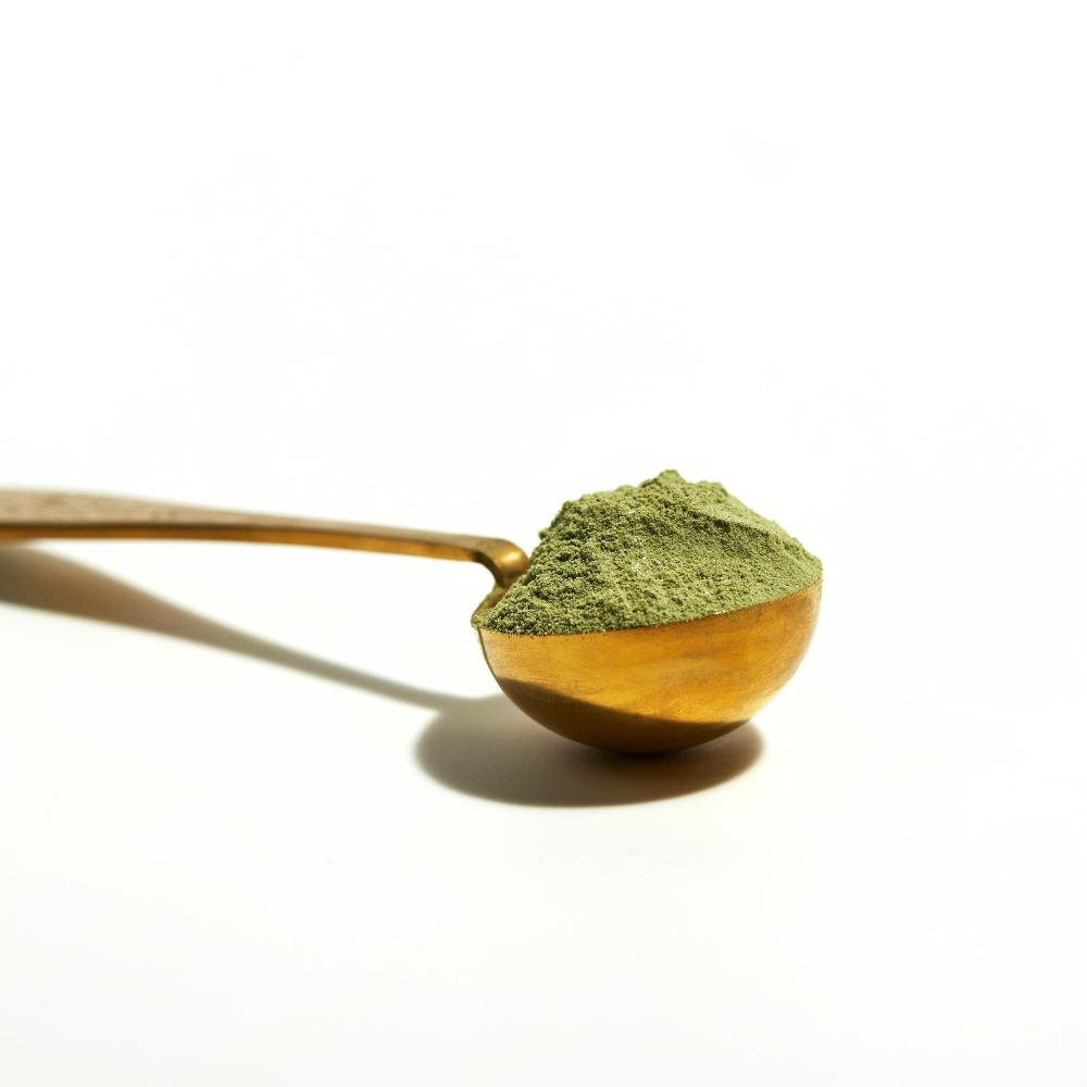 Gold spoon with heaped green powder flourish